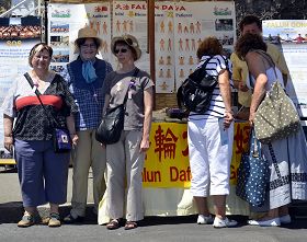 了解了真相的人们在法轮功展位前拍照留念