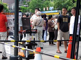 大陆游客正仔细观看法轮功学员播放的真相影片，一旁的郭伯伯（白头发）正与游客劝三<span