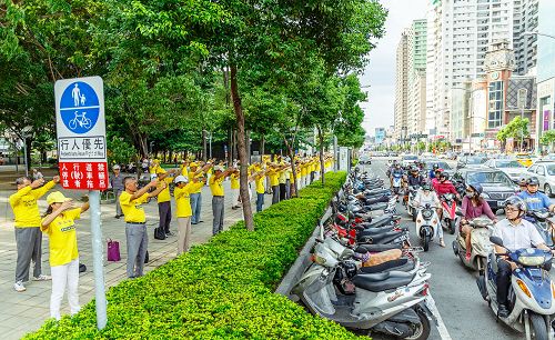 沿博爱路上“功法长城”,演示法轮功五套舒缓优美的动作;群众停下车子观赏。