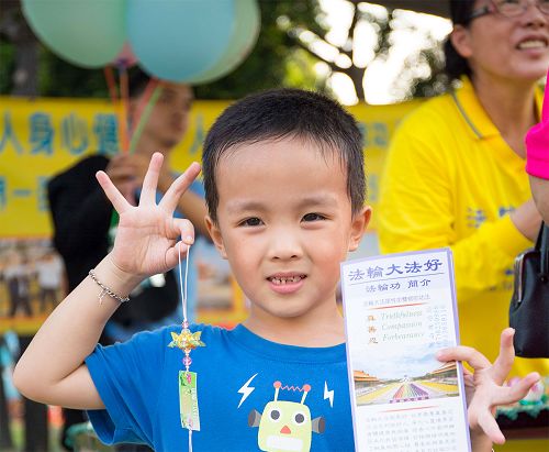 图7-10:两天中还设有法轮大法好弘法展位,有不少民众纷纷前来索取法轮大法简介传单、法轮大法莲花书签,并询问如何修炼法轮功。