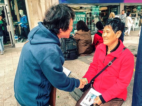 一位华人（右）抓住学员的手，对三<span style='max-width:0px!important;margin-left:-4px;color:#eee!important;'>:</span>退<span style='max-width:0px!important;margin-left:-4px;color:#eee!important;'>.</span>表示感谢