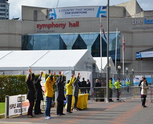 图1：英国执政党召开党代会年会期间，英国部分法轮功学员在会场外集体炼功，揭中共活摘罪行。