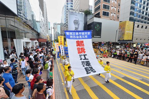 图15-20：法轮功学员希望民众了解真相，在游行队伍中打出了揭迫害、唤良知、启善念、劝三<span style='max-width:0px!important;margin-left:-4px;color:#eee!important;'>:</span>退<span style='max-width:0px!important;margin-left:-4px;color:#eee!important;'>.</span>，及全球控告迫害元凶江泽民等横幅。