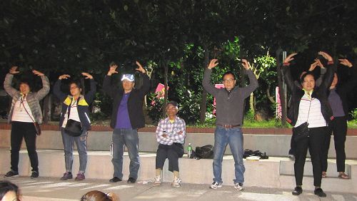 图6-7：法轮功学员演示五套功法，民众认真跟着学炼。