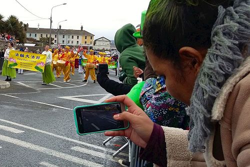 '图6:路旁的人们用手机拍照、录像法轮功的方阵'