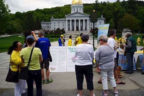 '图5:法轮功学员的活动吸引当地民众驻足观看,并阅读设立一旁的真相展板,了解什么是法轮功。'