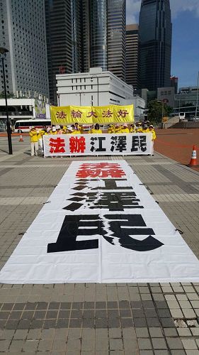 '图5～6：香港法轮功学员于三十日早晨，在爱丁堡广场集体炼功，并在正面遥对习*近*平住宿的海景万丽酒店方向，打出“法办江泽民”的巨型横幅。'