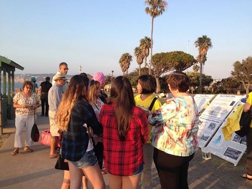 '图3~5:游人们纷纷驻足观看,阅读讲述法轮功被迫害真相的展板'