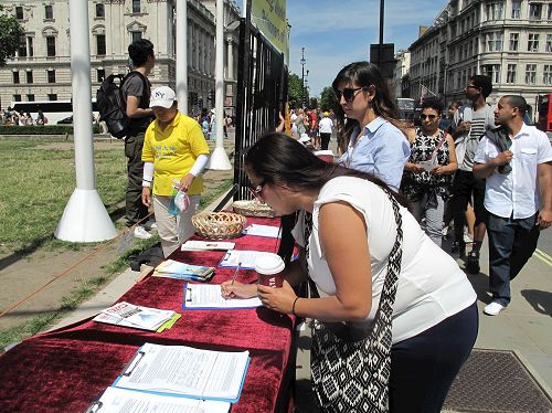 '图4：二零一七年七月十八日，美国游客利兹·卡萨诺瓦（Liz Casanova）在英议会大厦经过时，签名支持制止中共迫害法轮功及其活摘器官罪行。'