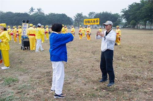 '图11:首次邂逅法轮功集会活动的林先生,在法轮功学员的指导下,学习五套至简至易的功法动作。'