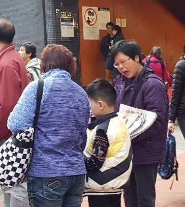 '图8:法轮功学员阿琼(右)在街头派发真相资料。'