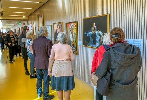 '图3～4：前来观看“真善忍美展”的来宾正在认真观画。'