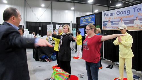 四月二十一日到二十二日,加拿大首都渥太华EY中心举办的身心健康展览上,法轮功学员为感兴趣的观众教功。