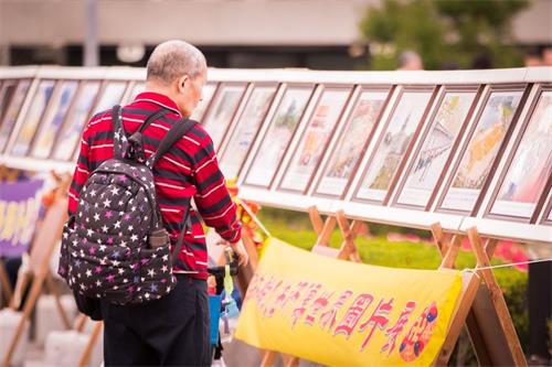 图:路人驻足观赏法轮大法洪传世界图片展。