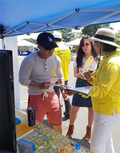 '图3：游客在法轮功展位前驻足听真相'