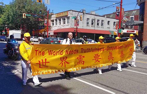 图11:温哥华著名博客主丹尼斯?沃森(Dennis Watson)与法轮功学员一起手持“世界需要真善忍”横幅走到游行终点。