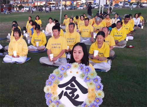 '图8～9：夜幕降临之际，法轮功学员们手持烛光排坐在草坪上举行烛光夜悼'