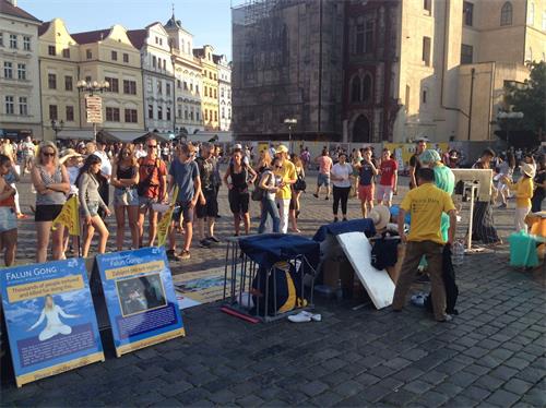 '图2:法轮功学员在老城广场向游人演示中共将法轮功学员放在囚笼里酷刑监禁'