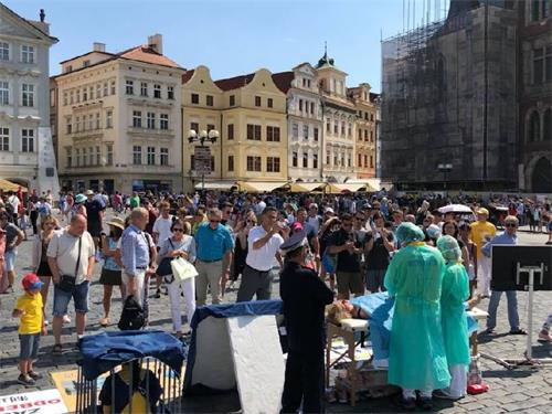 '图3:游人在老城广场前了解法轮功真相'