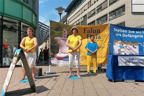 '图1:二零一八年七月二十八日中午,法轮功学员在在汉堡市中心的步行街史比塔勒街(Spitalerstrasse)上设立真相点,通过功法演示,展示大法的祥和与美好,同时揭露中共对法轮功学员的残酷迫害。'