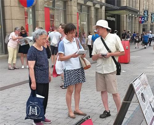 '图7:两个华人认真听法轮功学员(右)讲述中共自编自演的自焚伪案的真相。'