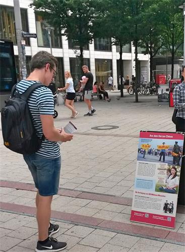 '图9:这位男士正在认真阅读展板,了解什么是法轮功,以及在中国中共对法轮功学员的迫害真相。'