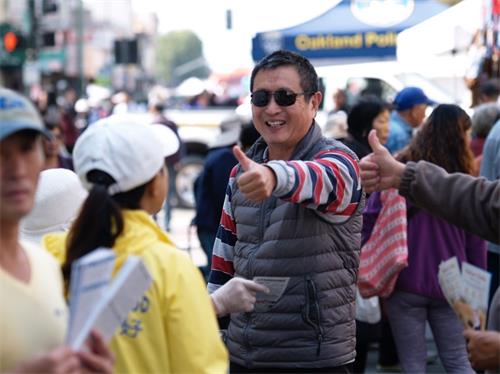 '图3:这位男士看到身穿印有“法轮大法好”字样黄色T恤衫的学员,就对学员竖起大拇指。'