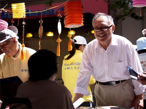 '图4:这位男士径直走到法轮功摊位,热情跟学员打招呼。'