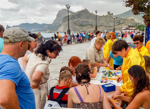 '图5~6:在真相点旁,法轮功学员还为小朋友们举办了“和平的花瓣”活动,教小朋友折莲花的同时,也教给他们以“真、善、忍”做一个更好的人。'