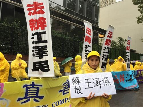 '图5:在当天的抗议活动中,来美六个月的山东义齿制造技师吕彩云手中举着一个牌子,两面分别写着“释放王海燕”和“释放徐秀娟”。'