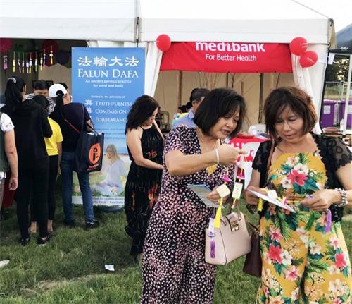 '图2:两位越南女士(右一,右二)高兴地阅读法轮大法真相资料'