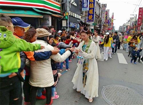 '图3~4:跟随天国乐团之后的仙女队由年轻法轮功学员组成,沿途发送法轮大法真相书签及小莲花给民众,民众如获至宝,满是欢喜。'