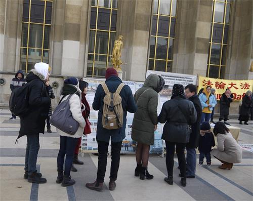 '图2~3:法轮功学员的活动引起了游人的关注,游人在观看真相展板'