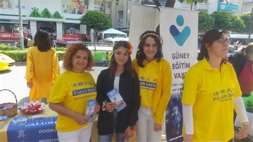 '图12:法轮功学员摊位的邻居塞纳(中)表示,学炼法轮功让她感到舒服'