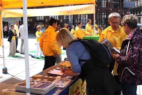 '图12:人们在要求制止中共政府活摘器官的请愿书上签字。'