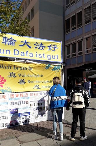 '图3:中国游客认真看法轮功真相展板'