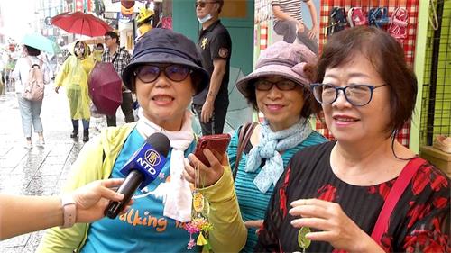 '图5～6：很多游客争先拿取印有“法轮大法好、真善忍好”的精美莲花纪念品，得到莲花的民众欣喜雀跃，彷若拿到吉祥如意的护身符，连连称谢。'