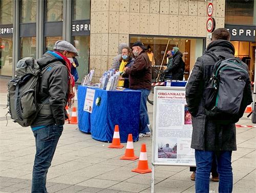 '图1~3:过往民众在法轮功学员摆出的信息台前了解信息以及和学员交谈了解真相。'