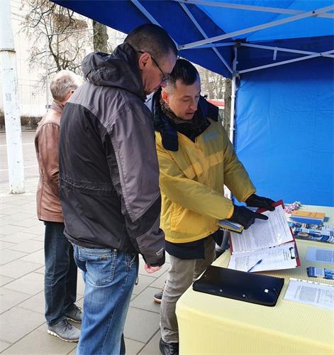 '图10:Arturas先生(左)听法轮功学员讲真相。'