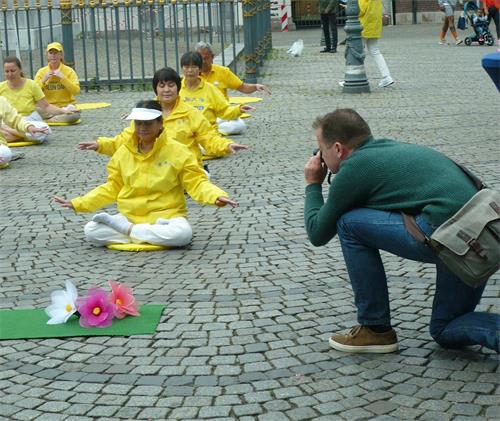 '图10:路人给正在打坐的法轮功学员摄影'