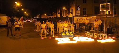 '图11~12:在中共大使馆前,学员们举行烛光悼念被中共迫害致死的同修,寄托哀思'