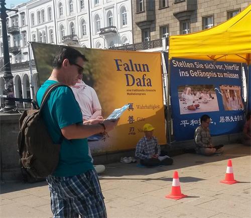 '图6~9:路人认真阅读法轮功信息点的展板和传单。'