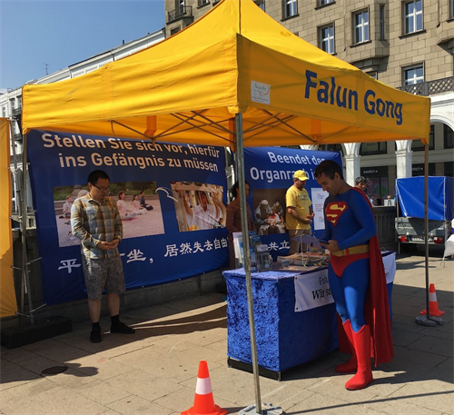 '图15:一位参与游行的人在信息点了解中共对法轮功的迫害'