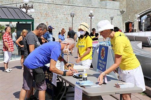 '图6~7:2020年8月22日,法轮功学员在魁北克省府魁北克市中心的杜维尔(D'Youville)广场传递真相,呼吁结束中共对法轮功长达21年的迫害。现场民众踊跃签署请愿信。'