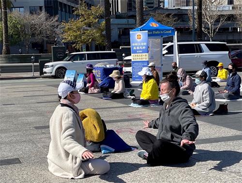 '图3:这位男士(前右)正在跟学员学炼法轮功第五套功法——神通加持法。'