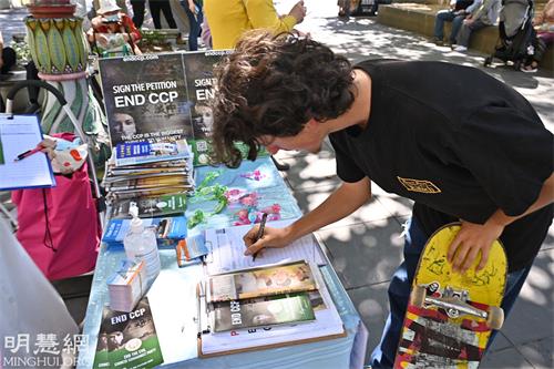 图1-3：二零二二年三月二十六日，澳洲墨尔本市中心举行集会声援3.9亿中国勇士三<span style='max-width:0px!important;margin-left:-4px;color:#eee!important;'>:</span>退<span style='max-width:0px!important;margin-left:-4px;color:#eee!important;'>.</span>，图为集会现场的民众驻足观看并签名反迫害。