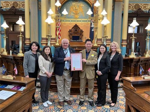 图1:州参议员戴尔·佐恩(左三)和部分法轮功学员代表,在决议案通过的议会大厅合影,并颁发第126号决议案