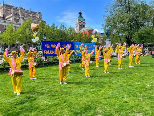 Ɗ，法轮功学员腰鼓队在表演“法轮大法好”，赢得观众阵阵掌声与喝彩。'