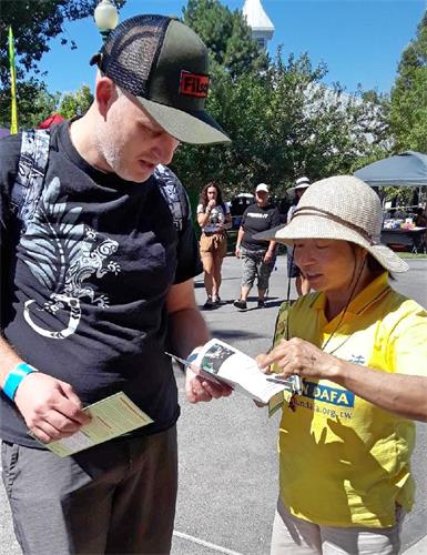 图2:学员给⽂化节的游⼈讲述法轮功的真相。