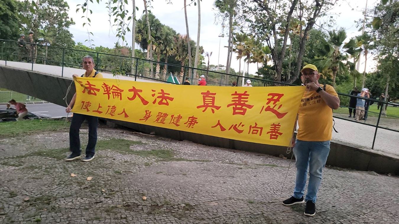 '图1~2:学员们举起反对中共迫害的真相条幅,要求中共立即停止强摘法轮功学员的器官。'